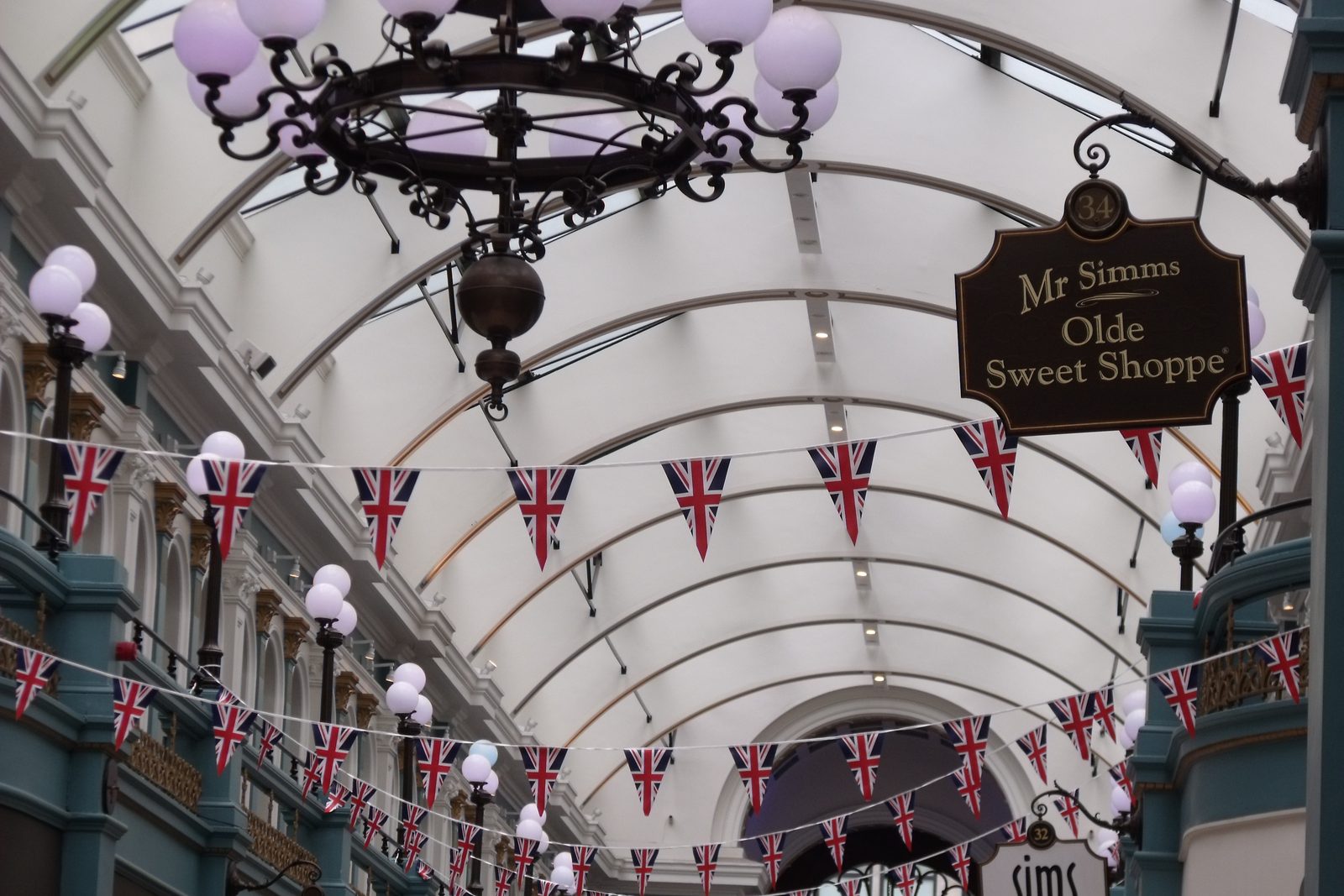 A covered British high street arcade lined with independent shops and hung with bunting